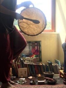 Photo of Jo playing her double sided shamanic drum during a drum healing