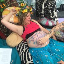 Photo of a pregnant woman having her belly painted