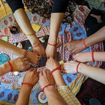 Photo of a group of women's wrists with red thread tied around them